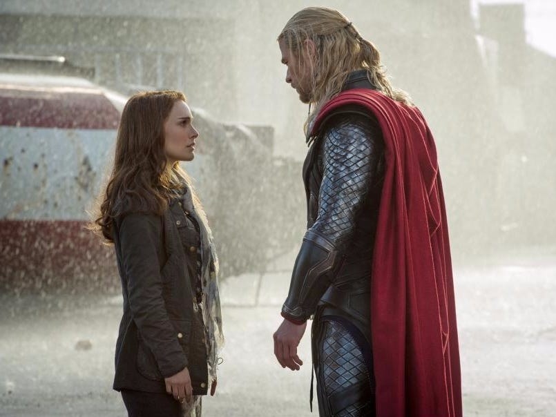 Chris Hemsworth as Thor and Natalie Portman as Jane looking at each other while standing in the rain.