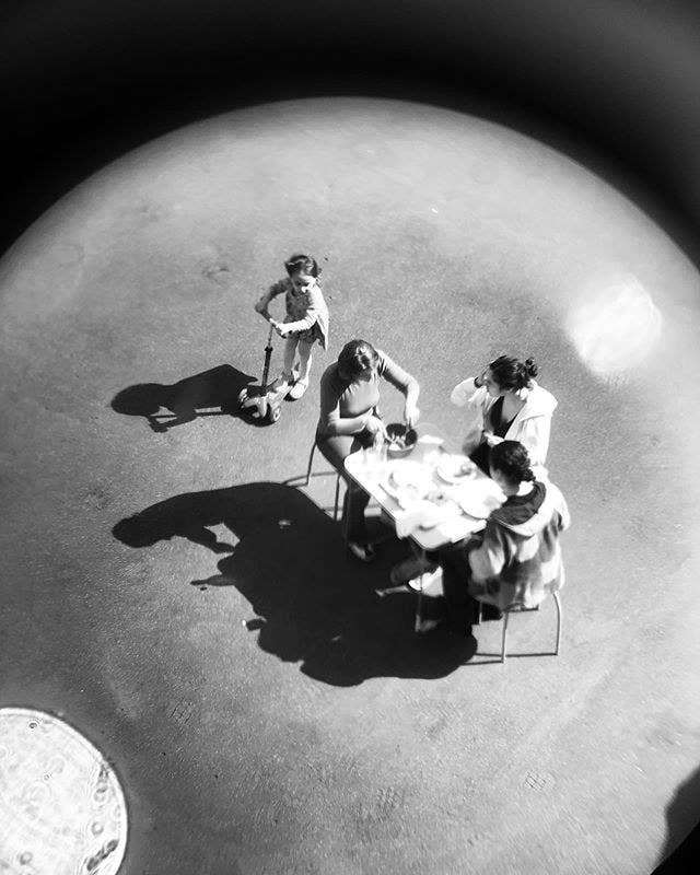Family of four has dinner at a table through a long lens