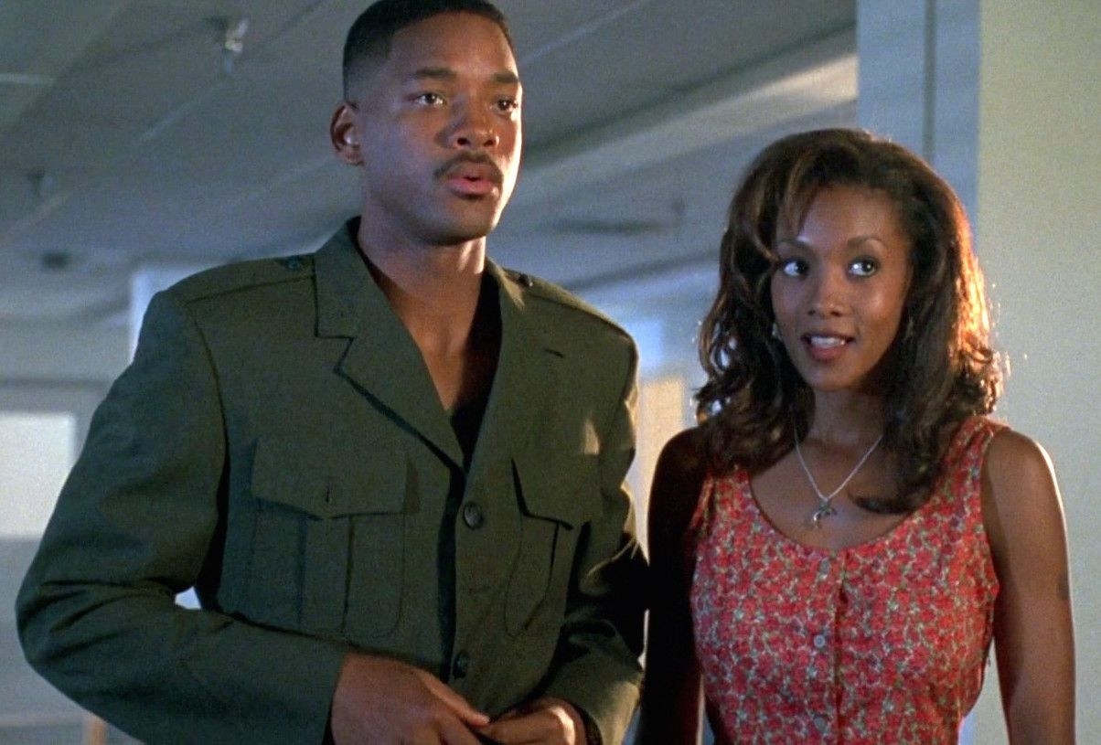 Will Smith as Steven and Vivica A. Fox as Jasmine stand next to each other looking confused.