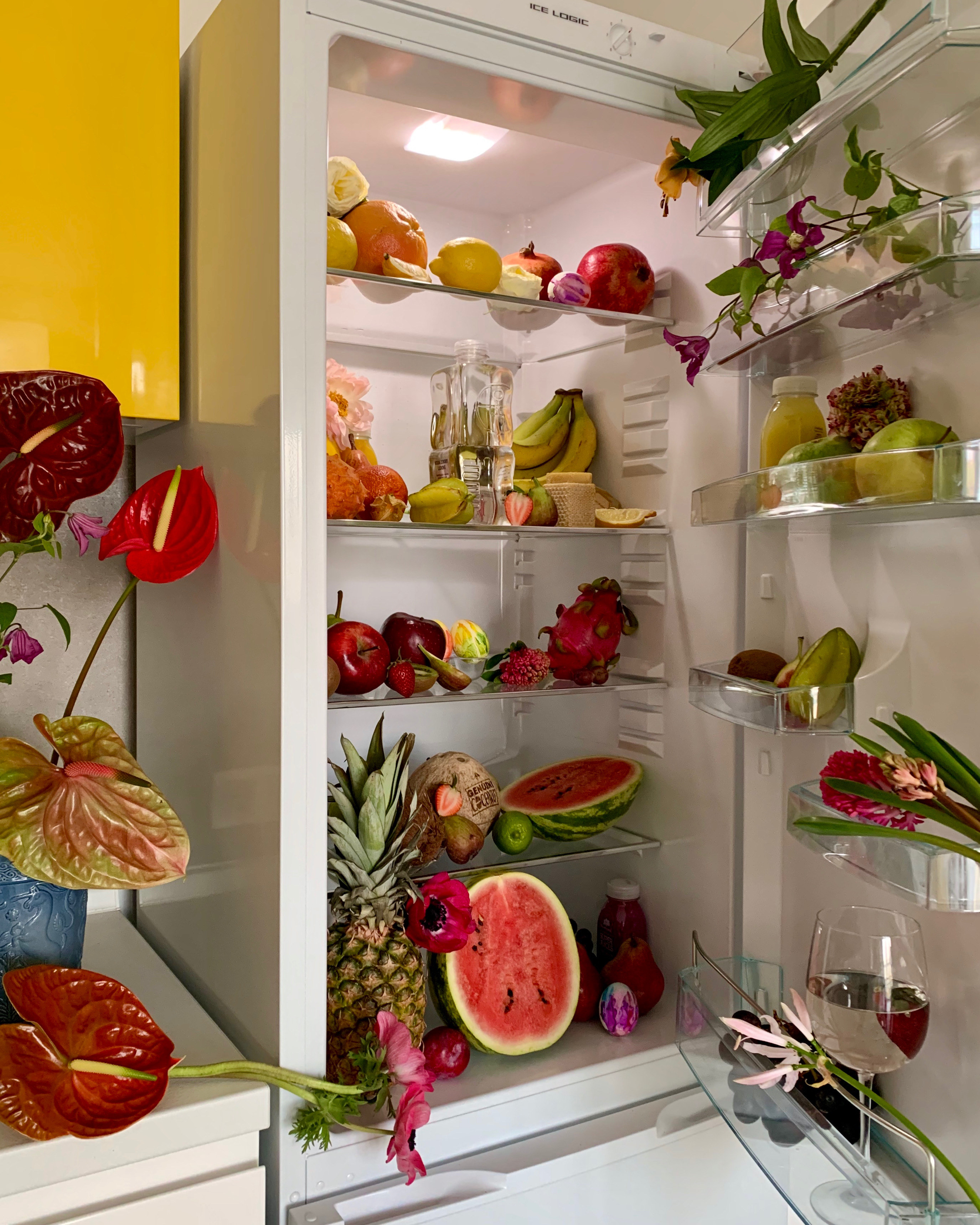 A fridge overflowing with fruit and flowers