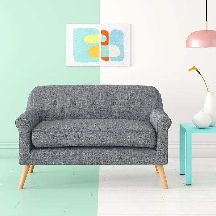 Flared arm loveseat in gray fabric with mid-century wooden legs 