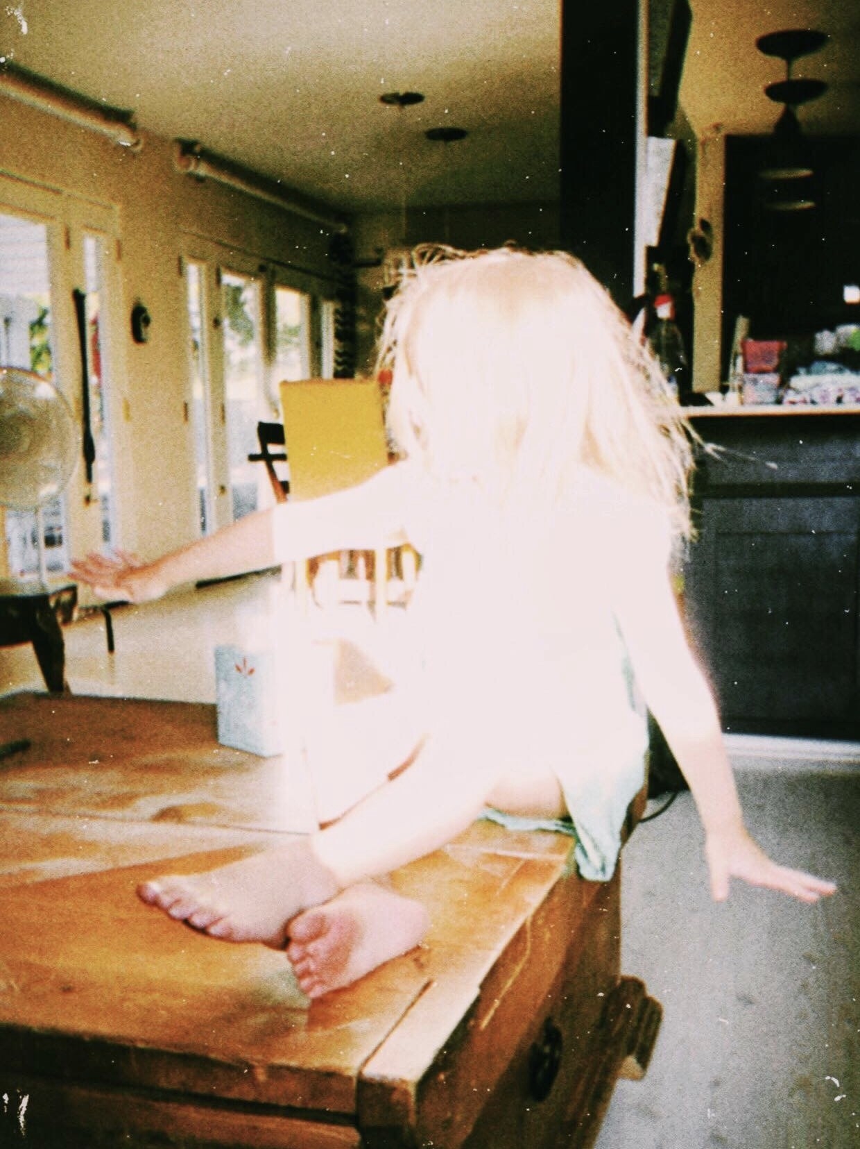 A child sitting on a table is blown out by flash 