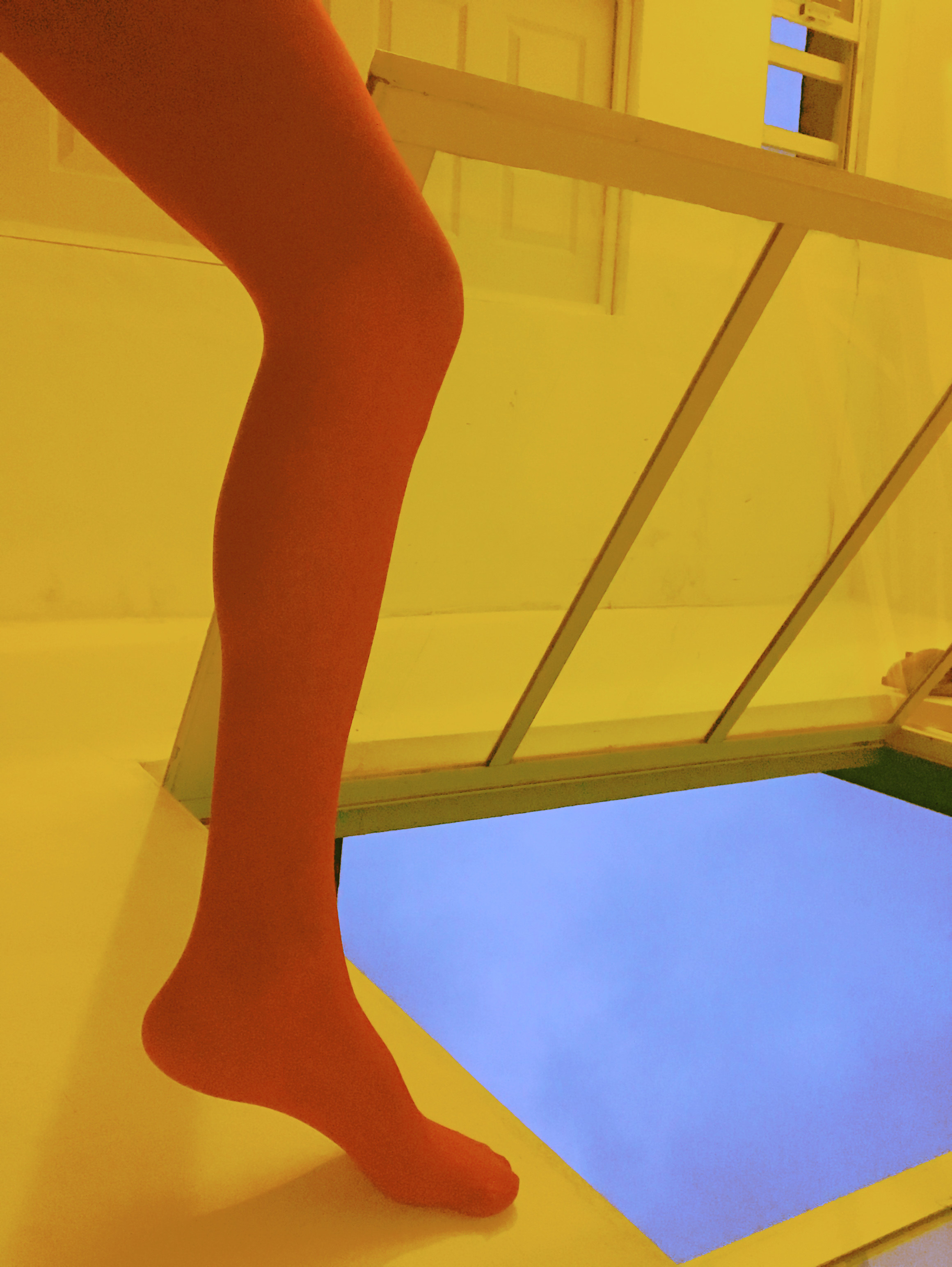 An orange leg next to a yellow wall and blue skylight