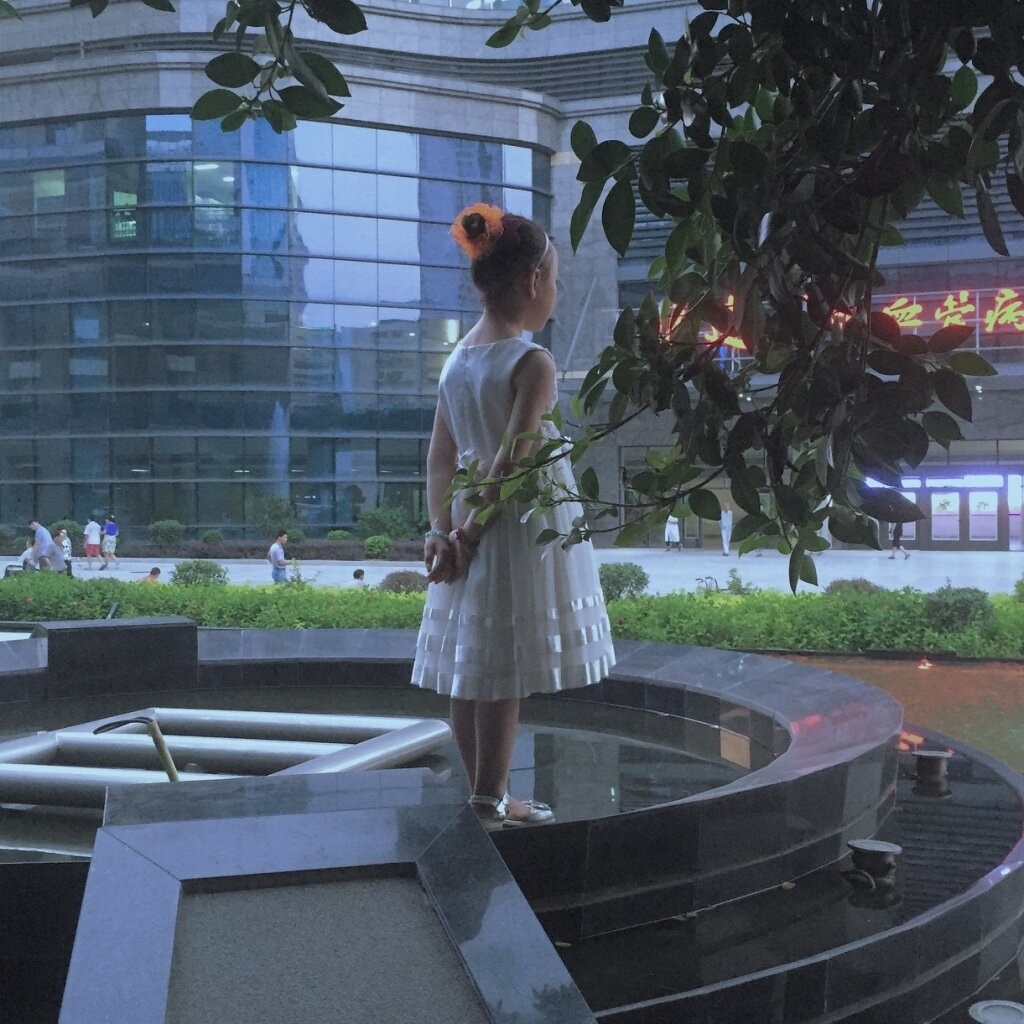 A girl in a white dress looks out at the street