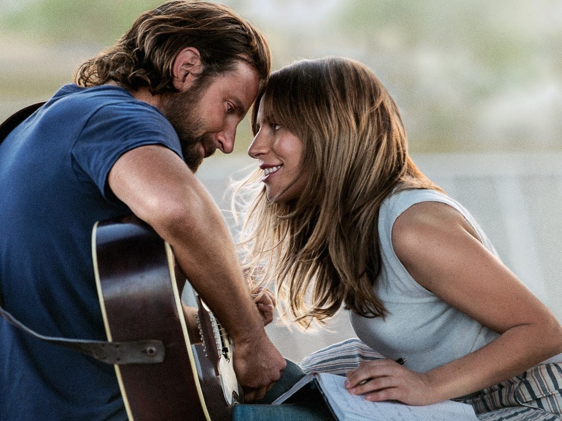 Lady Gaga as Ally leans in to kiss Jack (Bradley Cooper) while he plays the guitar.