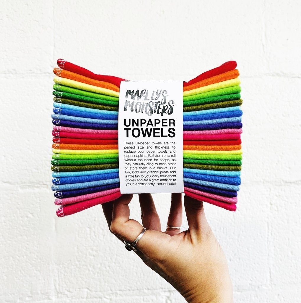 hand holding a pack of multi-colored towels labeled "unpaper towels"