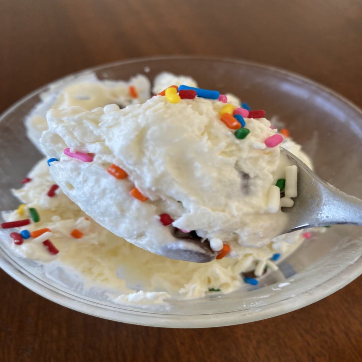A spoon dipping into a bowl of mason jar ice cream with rainbow sprinkles.