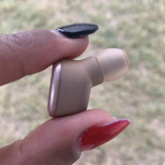 A reviewer holding up an earbud to show its size 