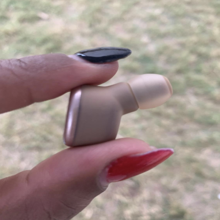 A reviewer holding up an earbud to show its size 