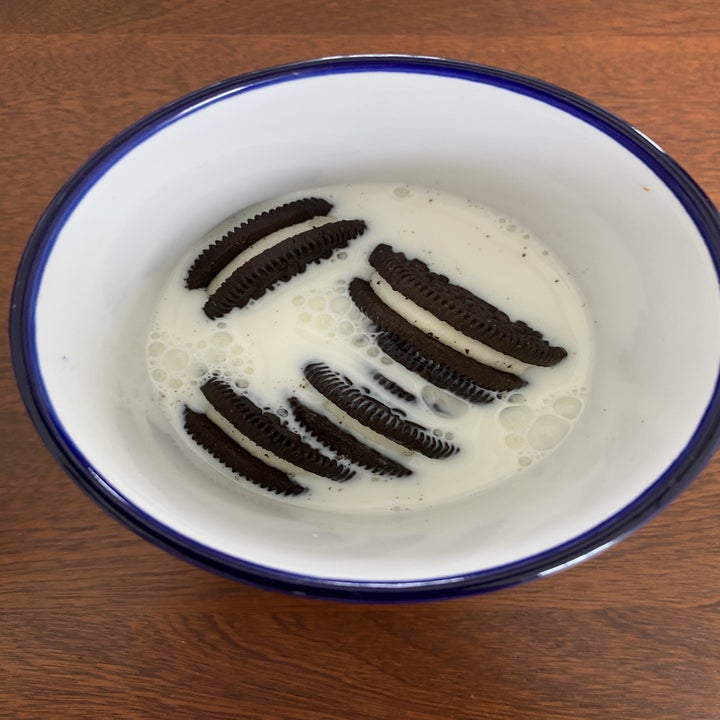 A handful of Oreos submerged in milk in a mug.