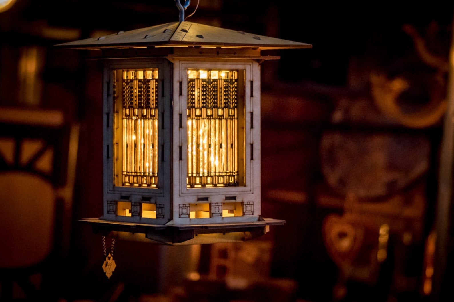 A wooden birdhouse with illuminated windows at night