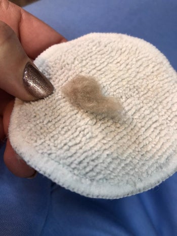 Another reviewer holding a cotton pad with a large ball of peach fuzz they shaved from their face