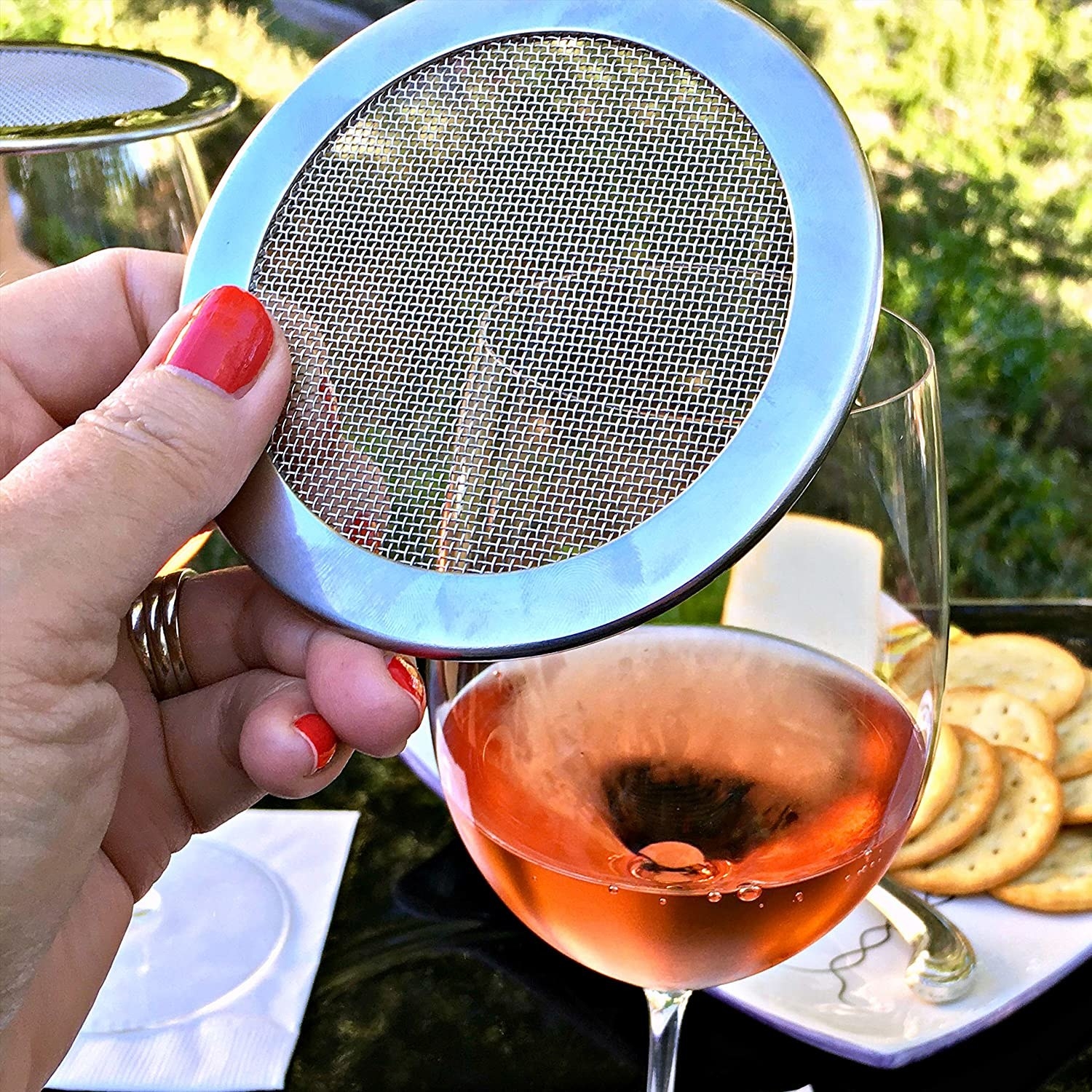 A person holding the mesh filer above their wine glass