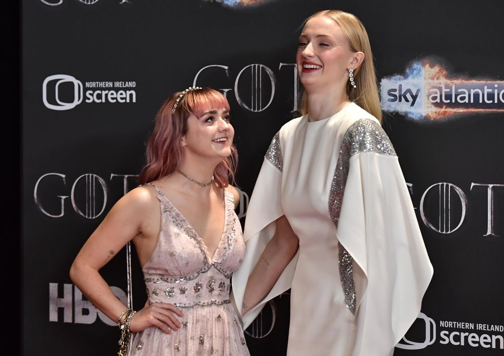 Maisie Williams and Sophie Turner smiling on the red carpet together.