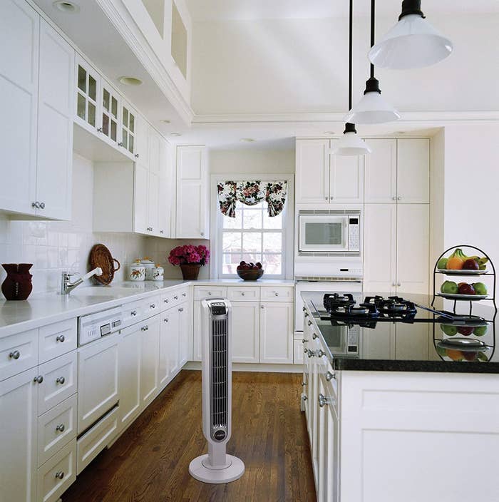 White oscillating tower fan placed in kitchen 