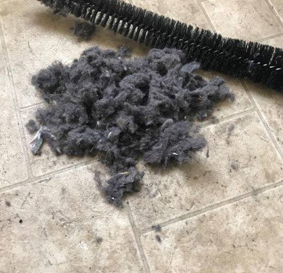 Reviewer's picture of the vent-cleaning brush next to a large pile of lint