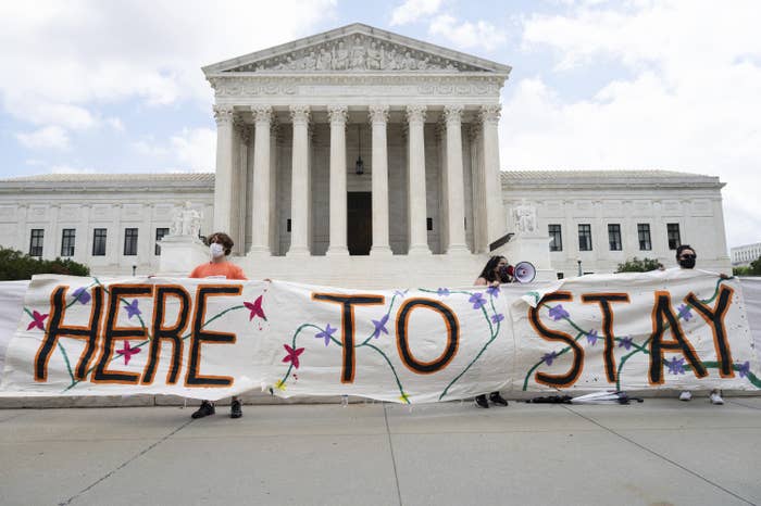 Demonstrators hold up a sign reading &quot;Here to Stay&quot; in front of the US Supreme Court building