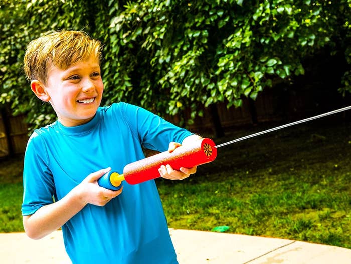 Child model spraying water from red foam blaster