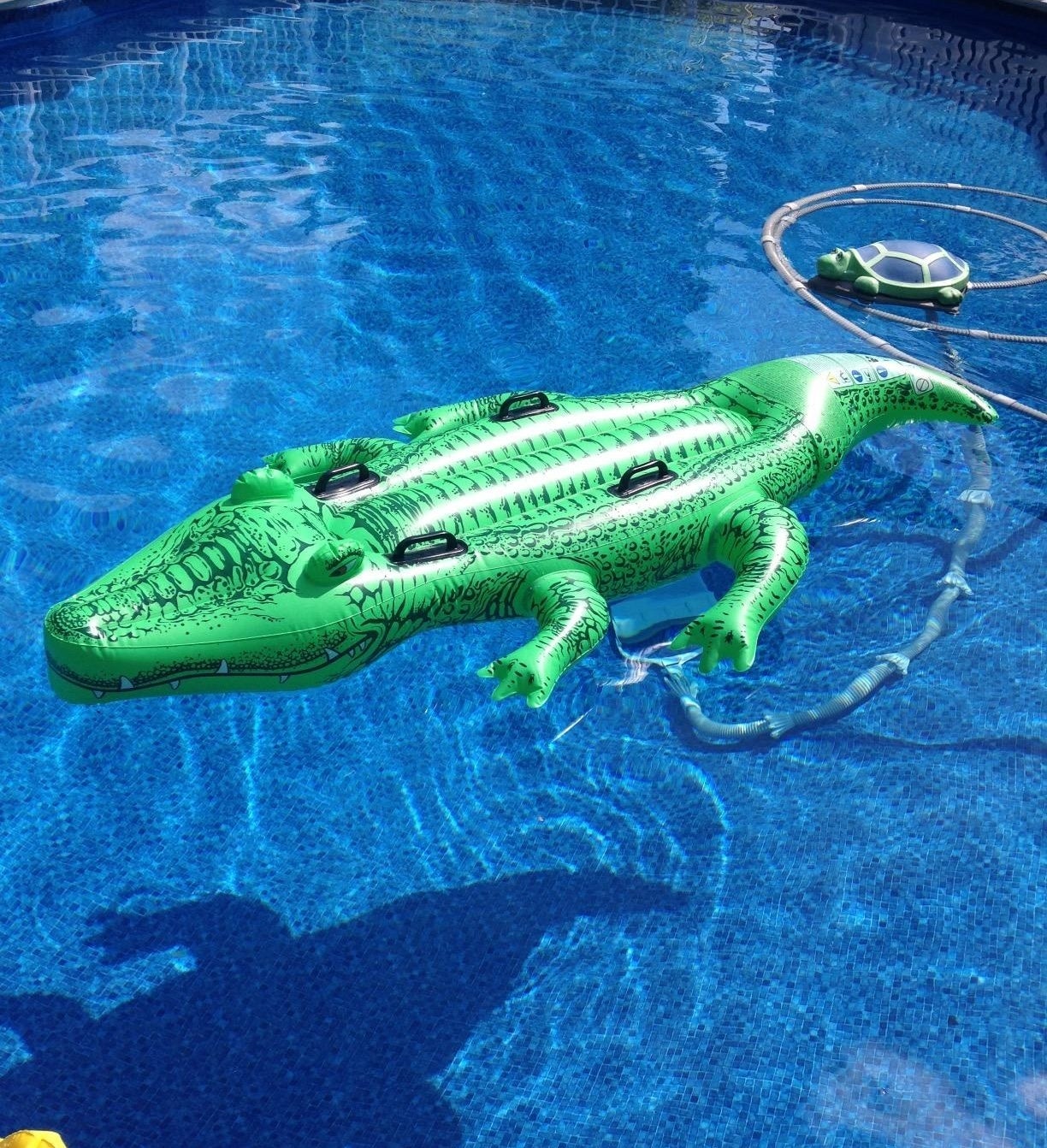 A green alligator pool float with black handles