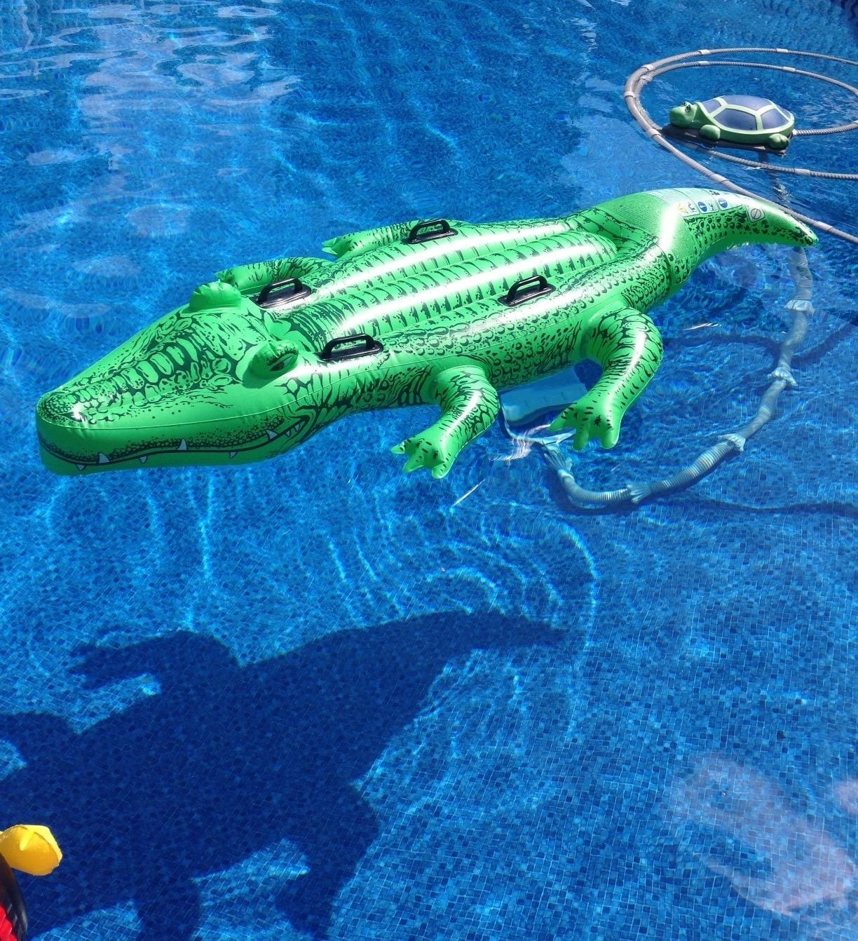 A green alligator pool float with black handles