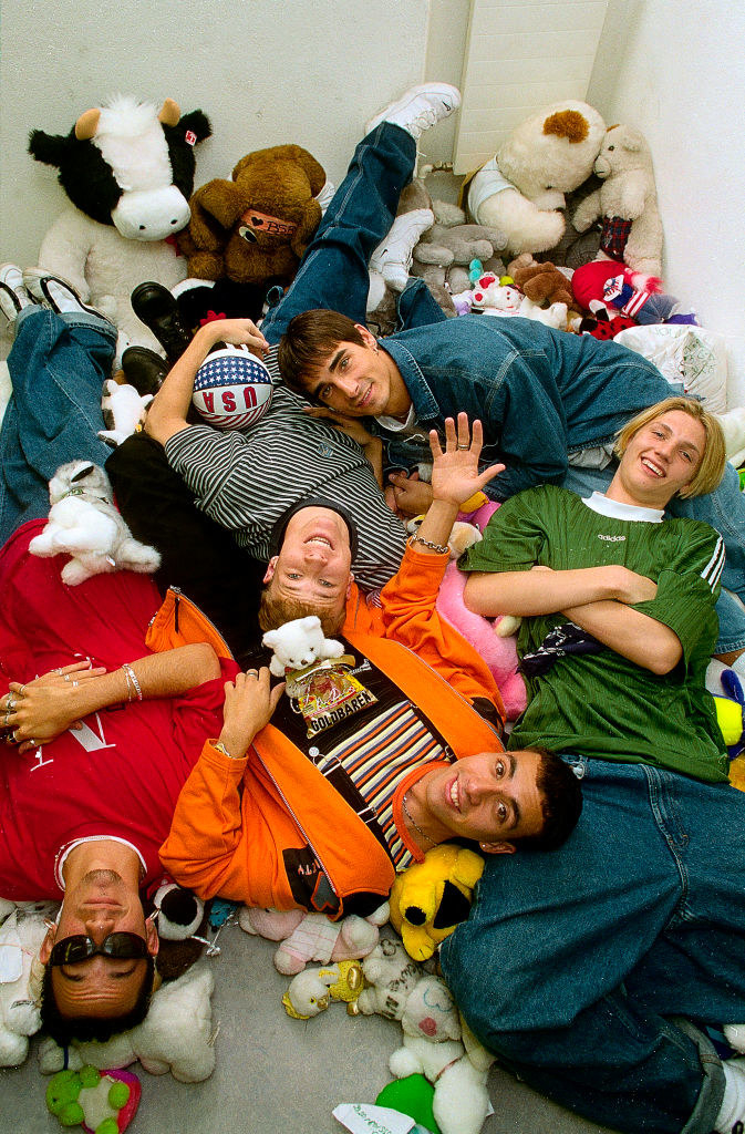 A photo of the Backstreet Boys lying on a bunch of stuffed animals.