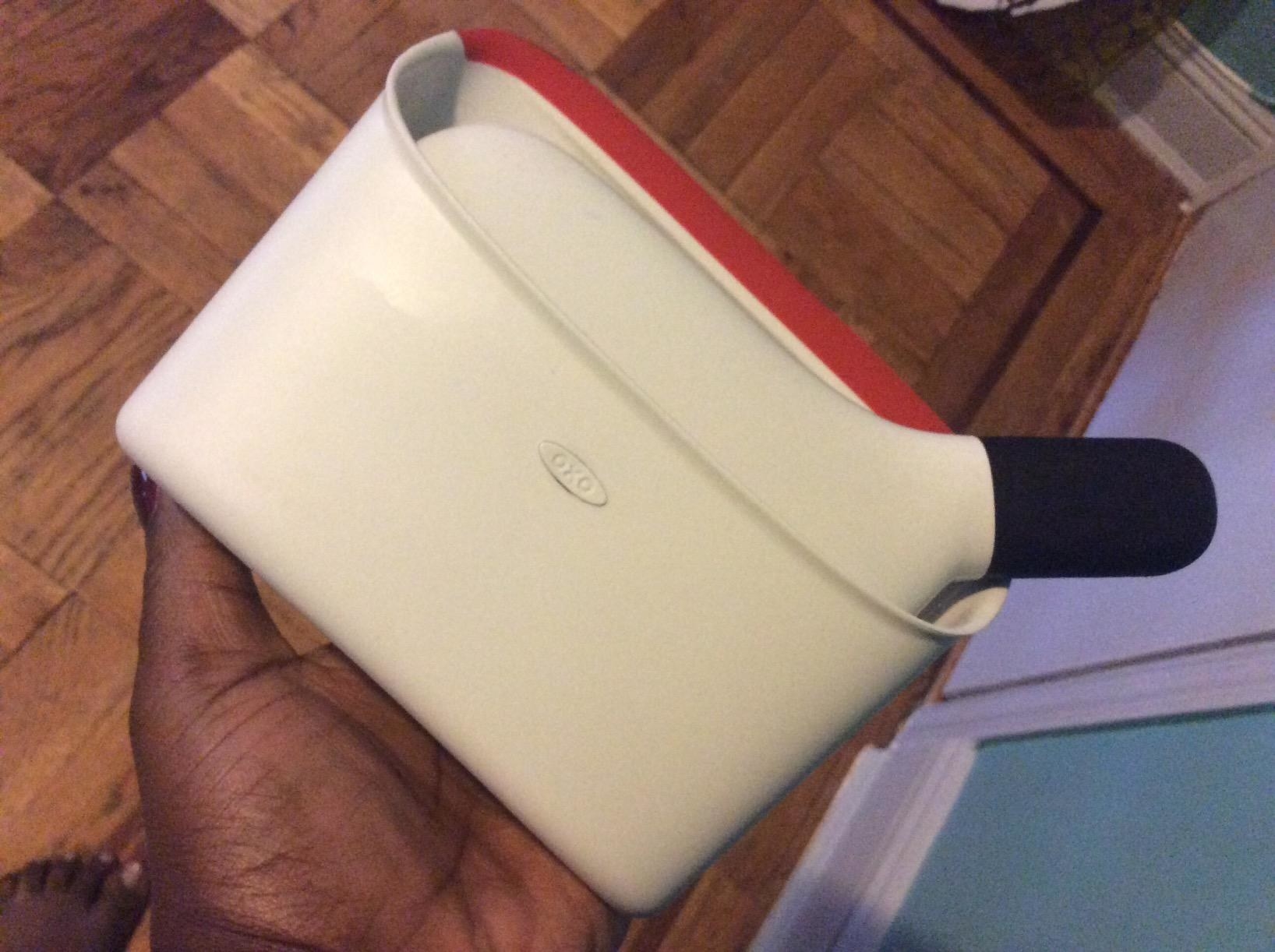 reviewer holding a small dustpan in the palm of their hand with a tiny broom inside. 