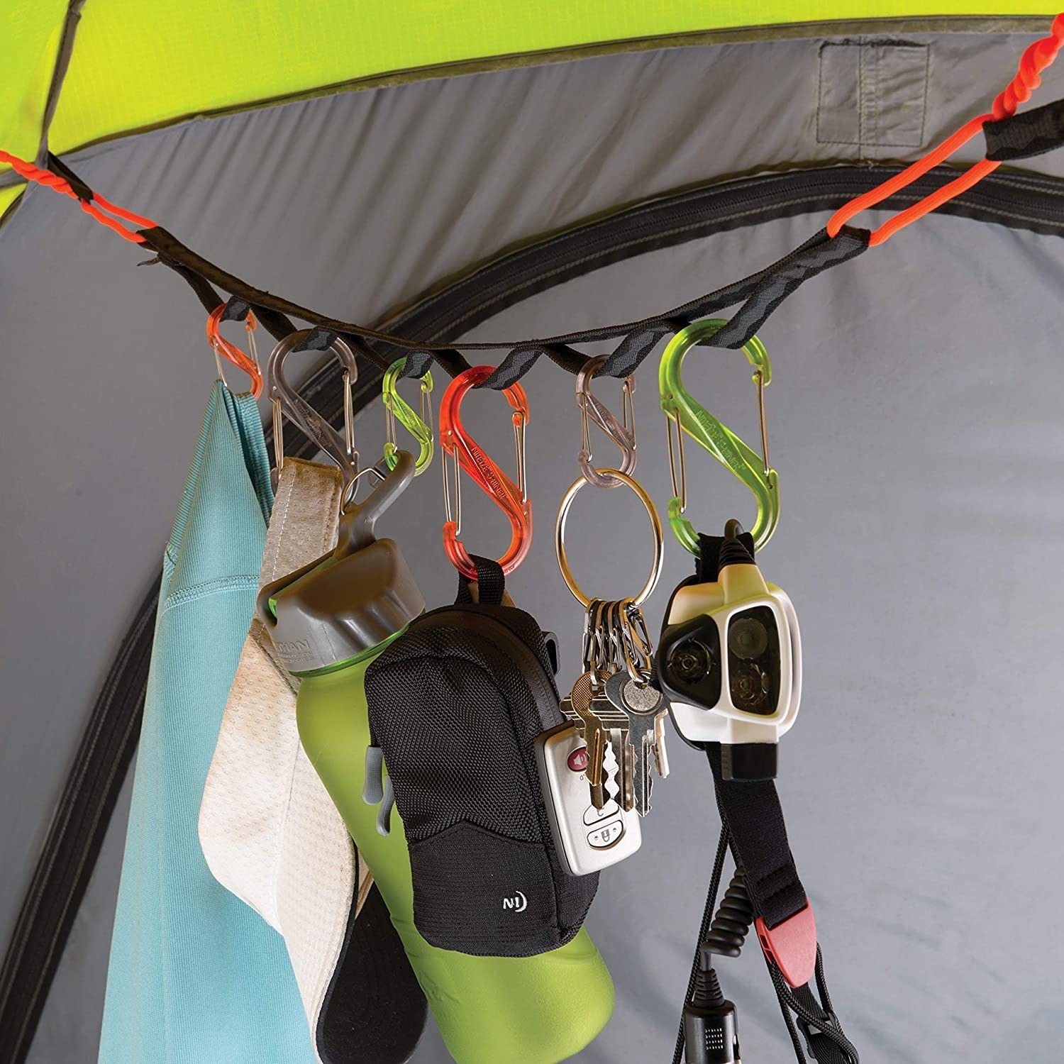 strap with fabric rings attached to tent ceiling with twist ties hanging S-Biners and carabiners hlding gear like water bottles, hats, and keys