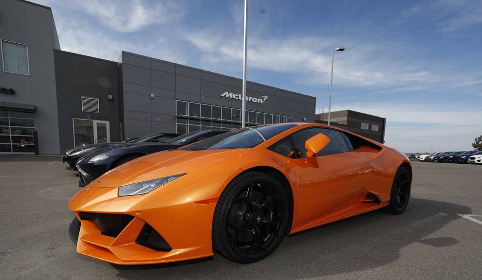 An orange sports car is parked at a dealership