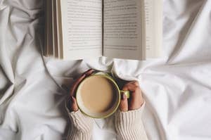 A mug of coffee and an open book against a white blanket