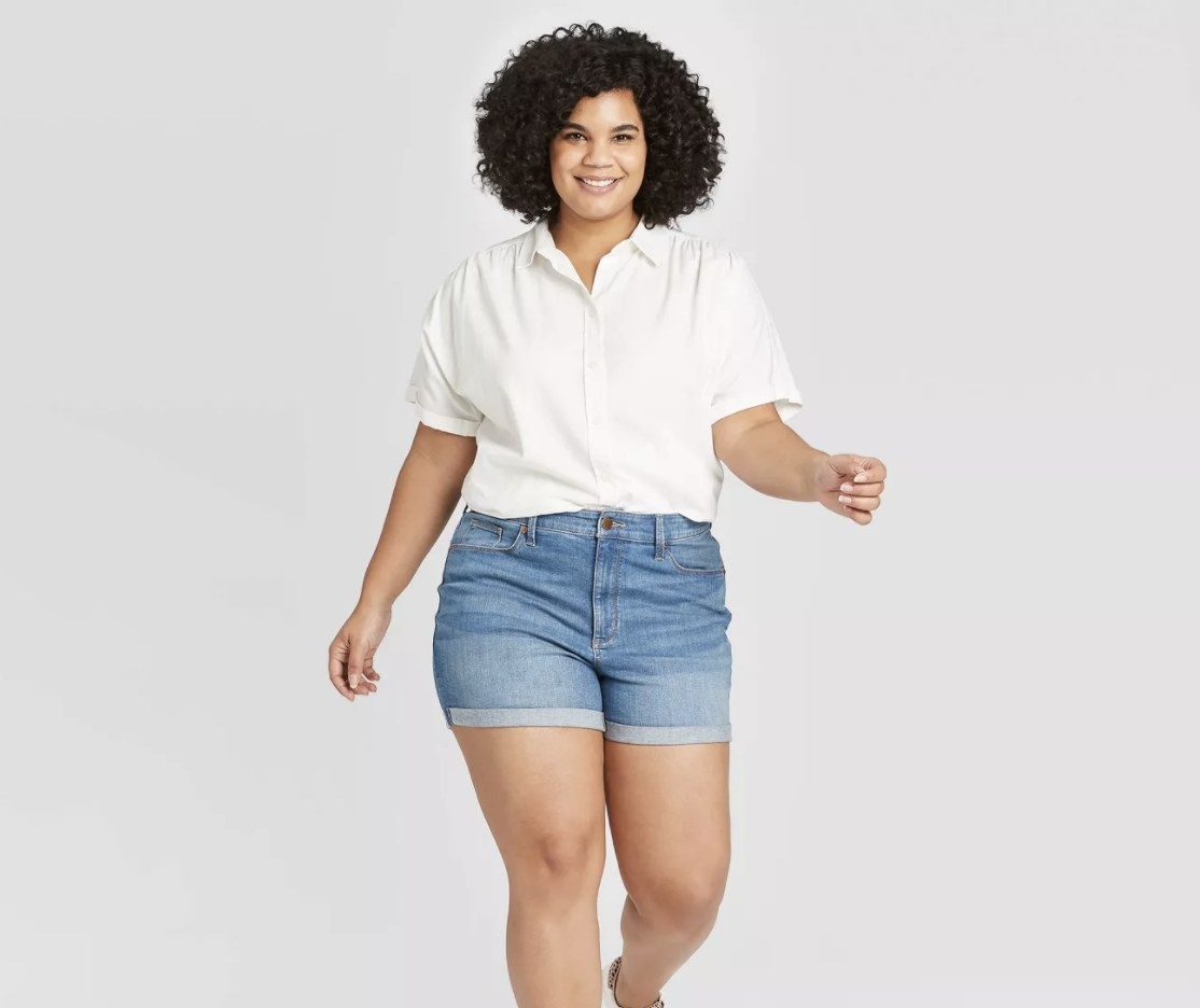 A model wearing medium-wash denim shorts that hit mid thigh