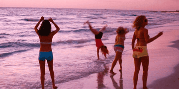 Four girls frolic on the beach at dusk and one does a cartwheel. From the movie Spring Breakers