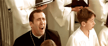 A gif showing Nicolas Cage doing a maniacal expression in a church scene from the movie Face Off