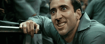 A gif showing Nicolas Cage doing a maniacal expression in a prison scene from the movie Face Off