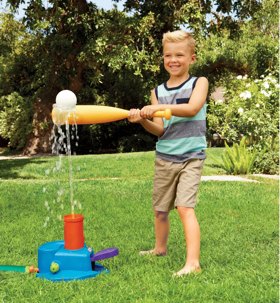 A child model swinging a yellow plastic bat at a white ball being pushed into the air by a stream of water