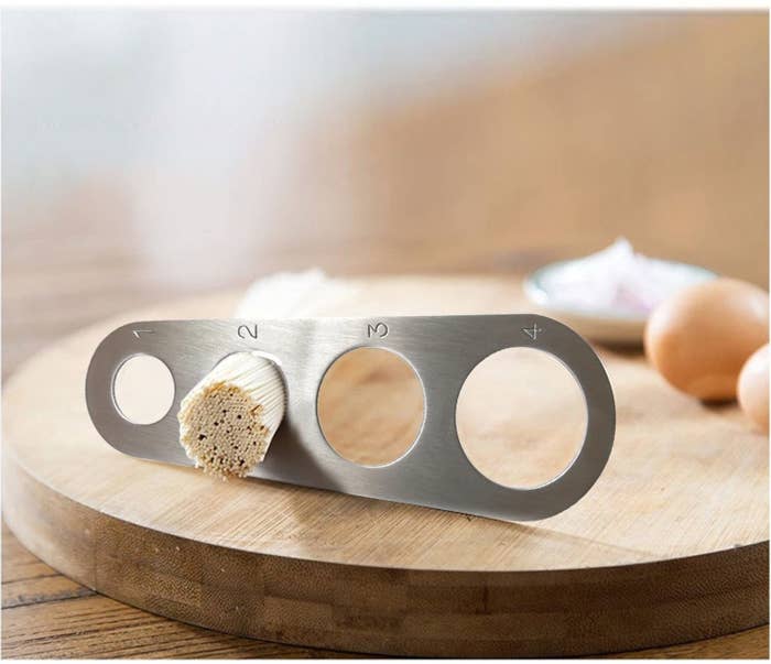 The tool with four differently sized holes to measure pasta meant for one, two, three, or four servings