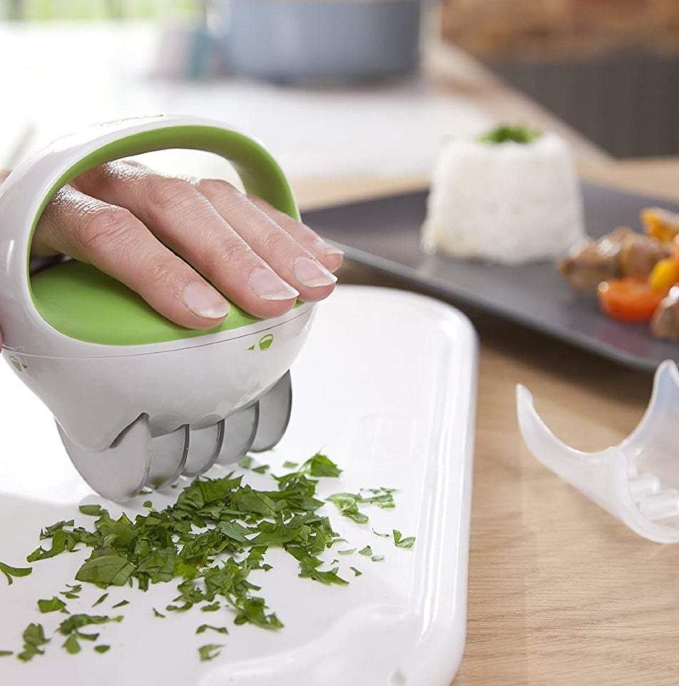 A person mincing herbs with the herb chopper