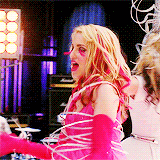 Quinn dancing in a bright dress with matching gloves and long false eyelashes