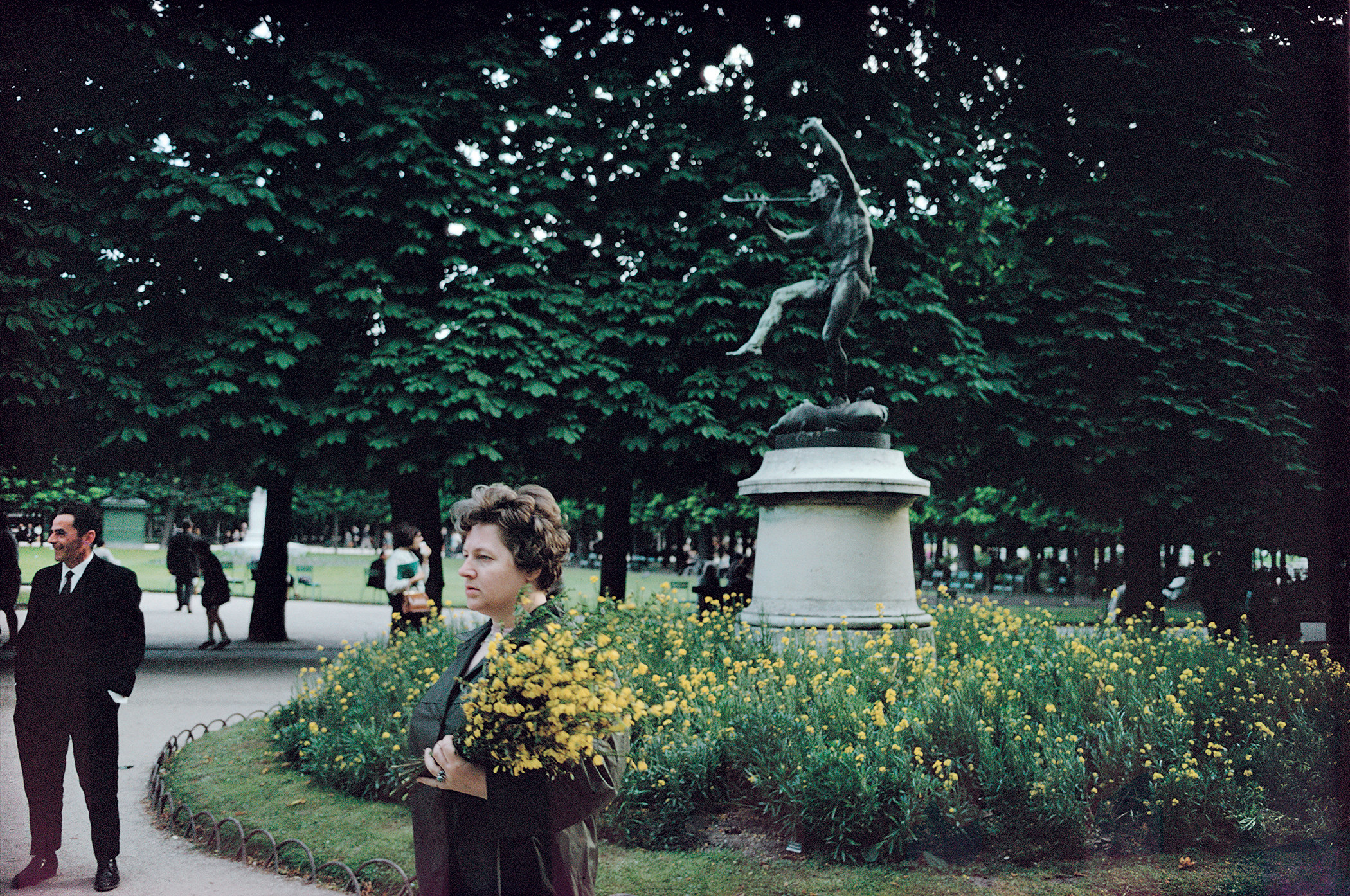 A woman carries flowers through a city park