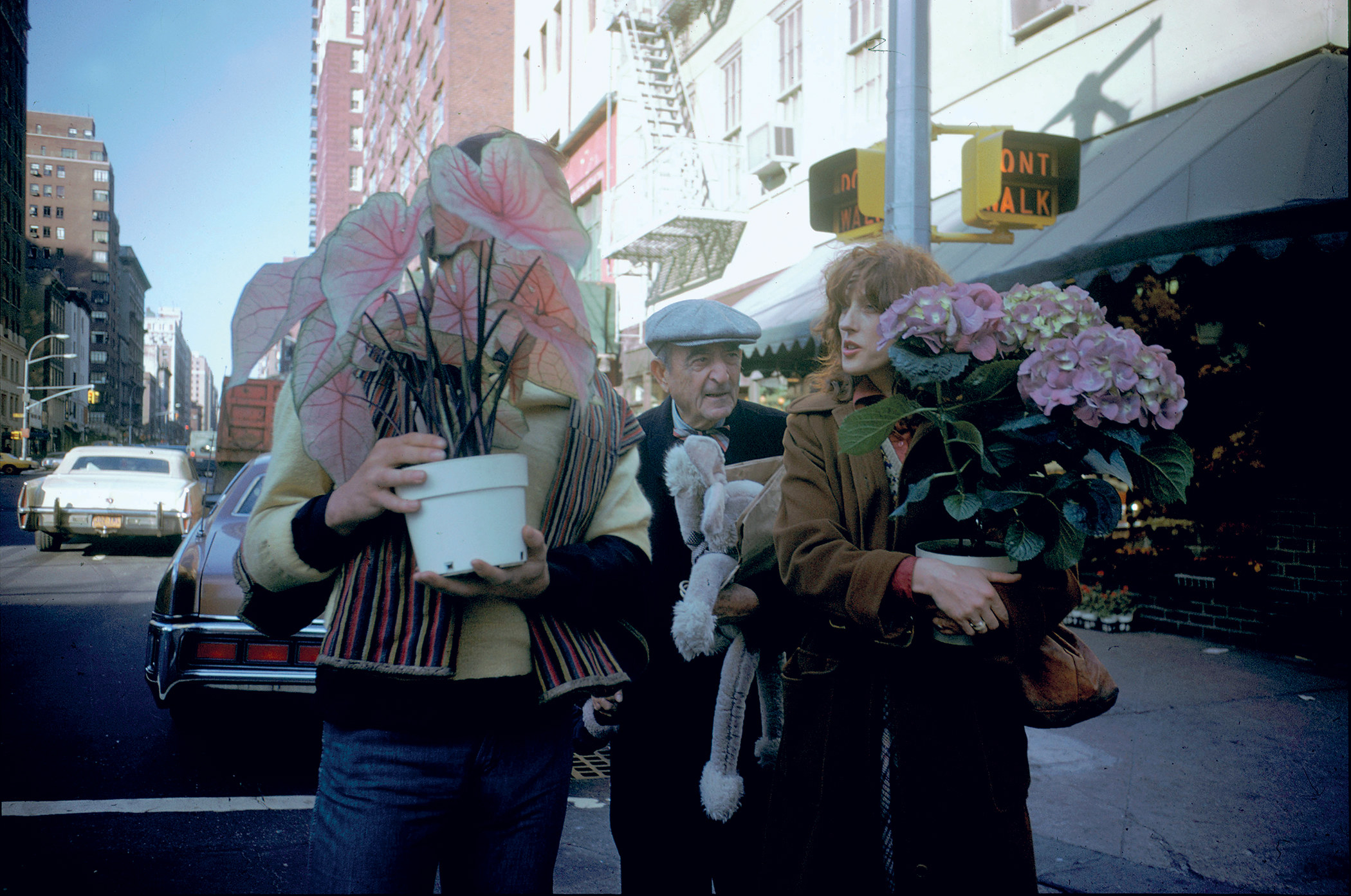 A man and a woman carry flowers on a city street