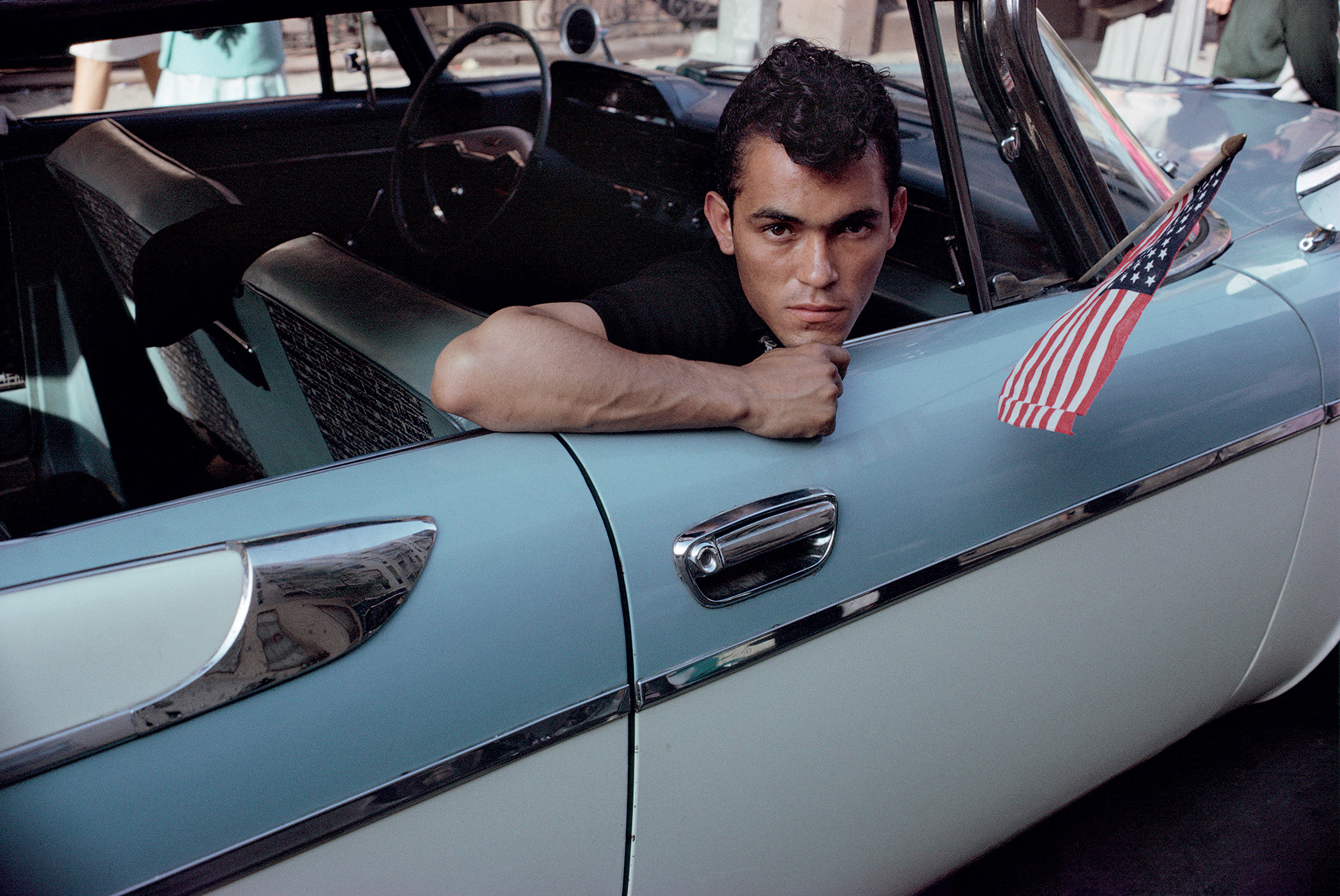 A young man rests in the passenger seat of a classic car