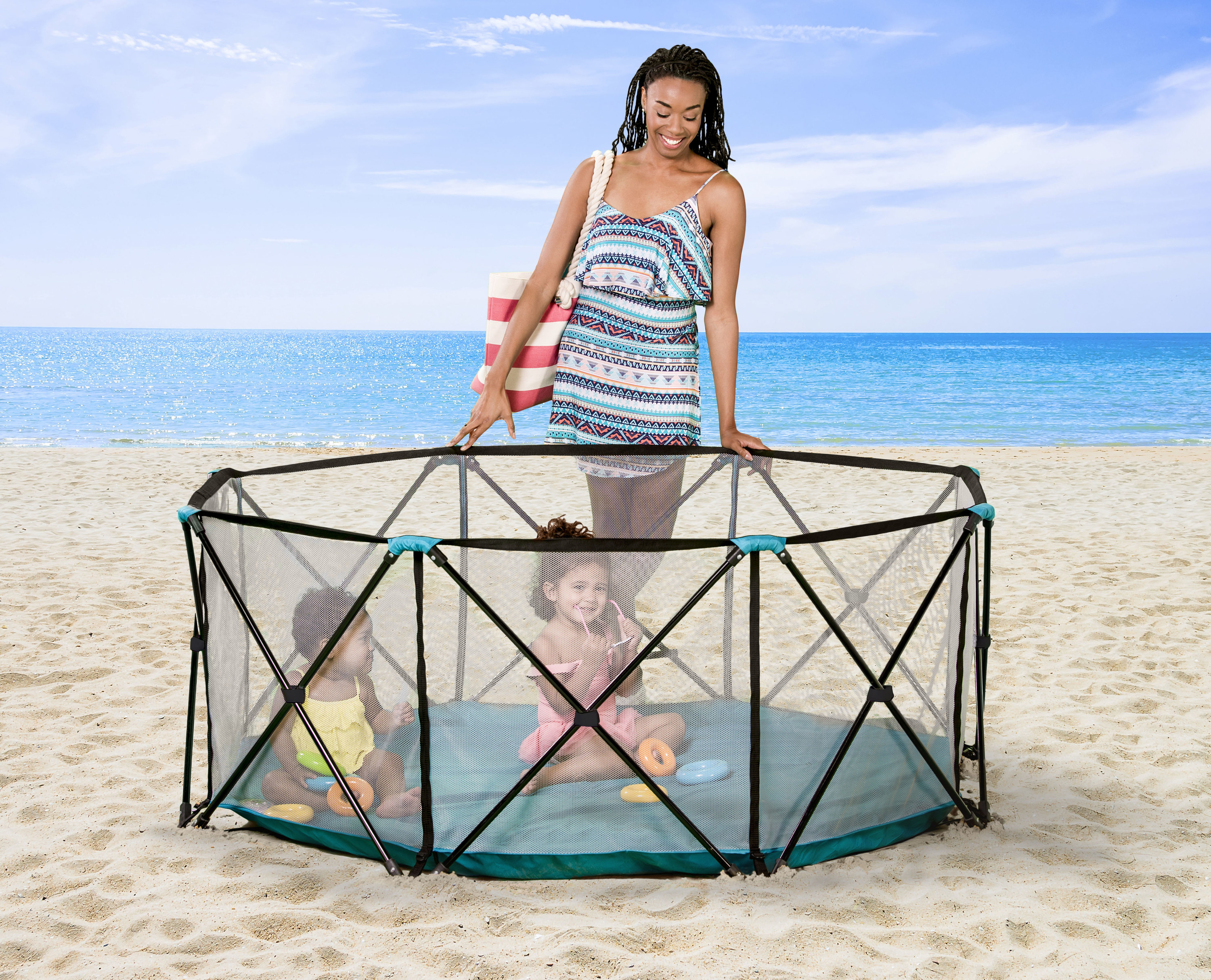 Model looking over two children in a black and teal see-through play pen