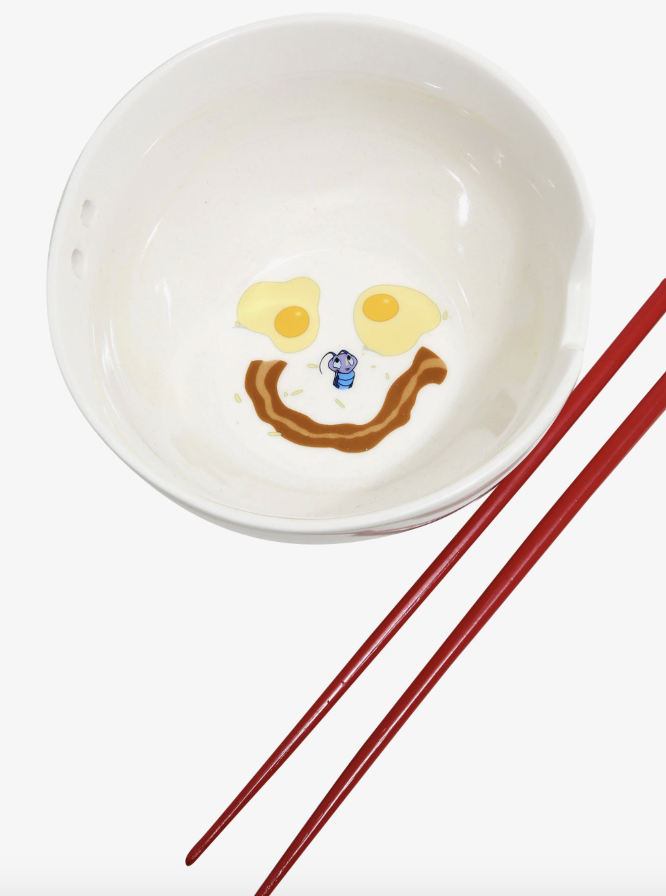 a bowl with the eggs and smile made of bacon drawn on the inside in addition to kri-kee from the movie mulan alongside red chopsticks
