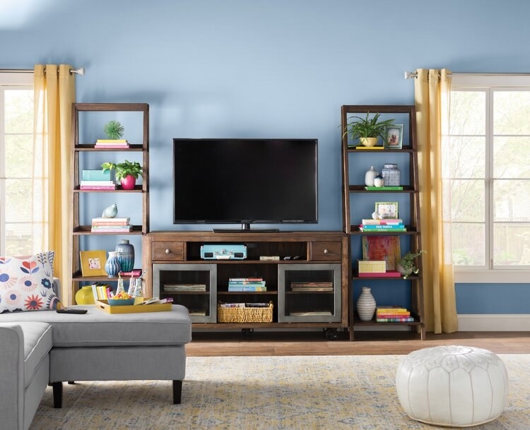 A living room with a TV on an entertainment stand, bookended by two shelves