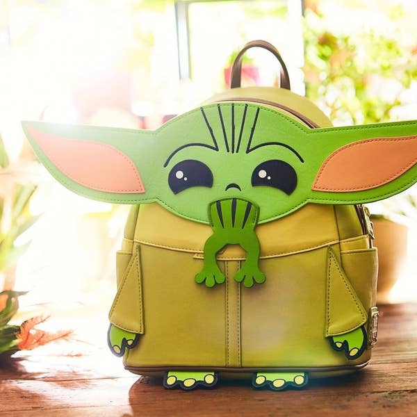a tan and green backpack of baby yoda eating a frog