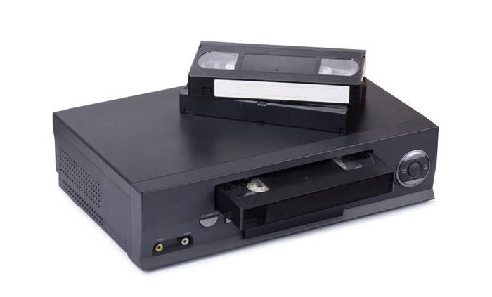 A stock image of a VCR with two VHS tapes on the top of it.