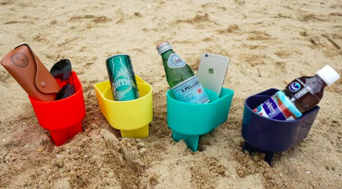 Red, yellow, green, blue, and navy beach cup holders with beverages in the sand