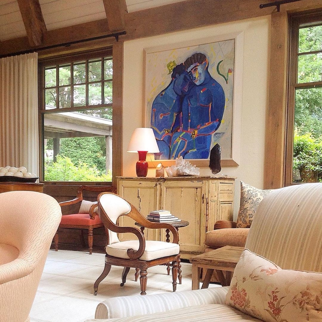 A large piece of artwork depicting blue people hangs above a wooden credenza