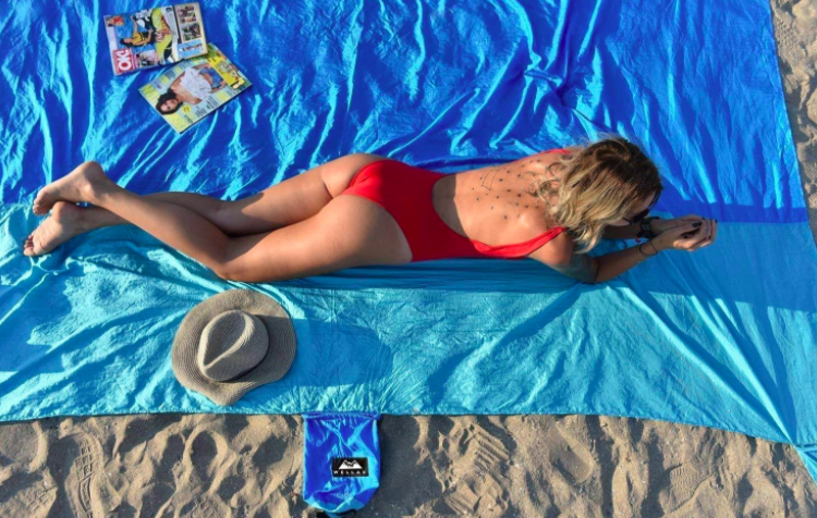 Woman in red swimsuit lies on a blue beach towel 