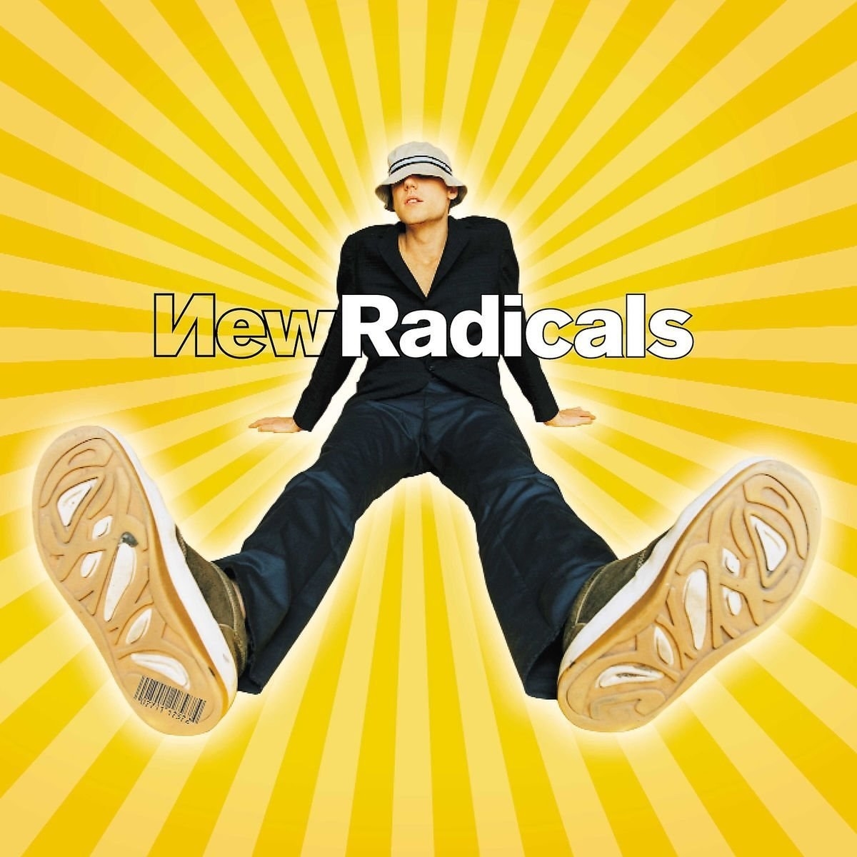 The album cover to &quot;Maybe You&#x27;ve Been Brainwashed Too&quot; by the New Radicals, which features a yellow star burst background and the lead singer Gregg Alexander sitting with a bucket covering his eyes and the bottom of his shoes facing closet to the camera.