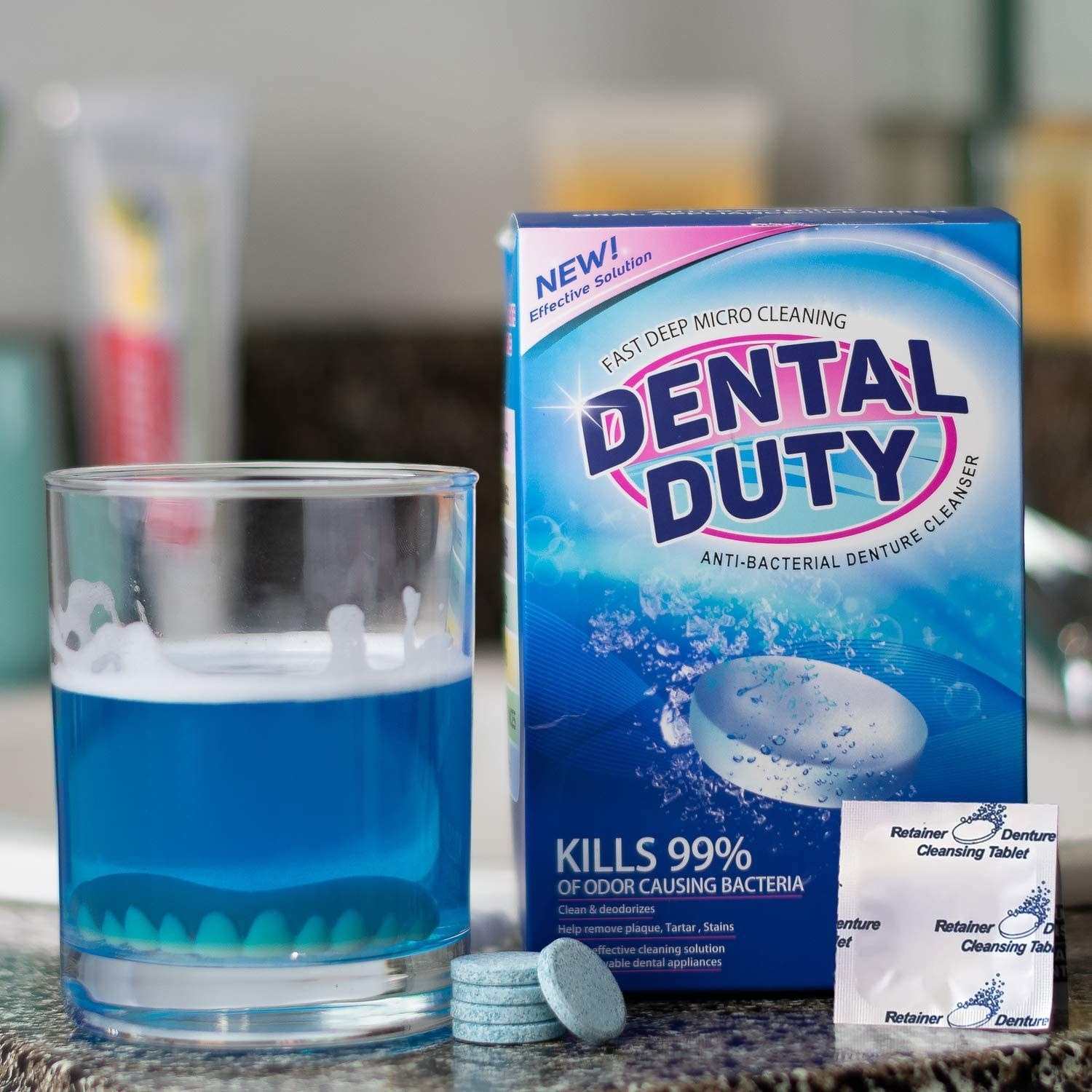 A pack of dental duty tablets next to a glass with dentures in it